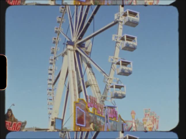 Footage of a ferris wheel in an amusement park with various people