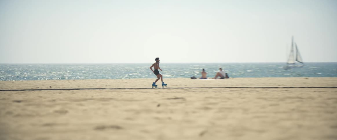 A man is rollerblading on the beach