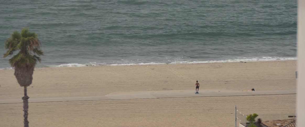 Young man dancing with roller skates on the beachside sidewalk during the summer