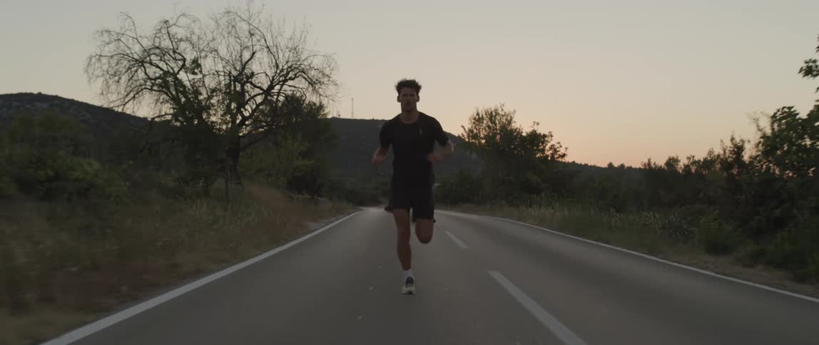 A man jogging on a road at dusk