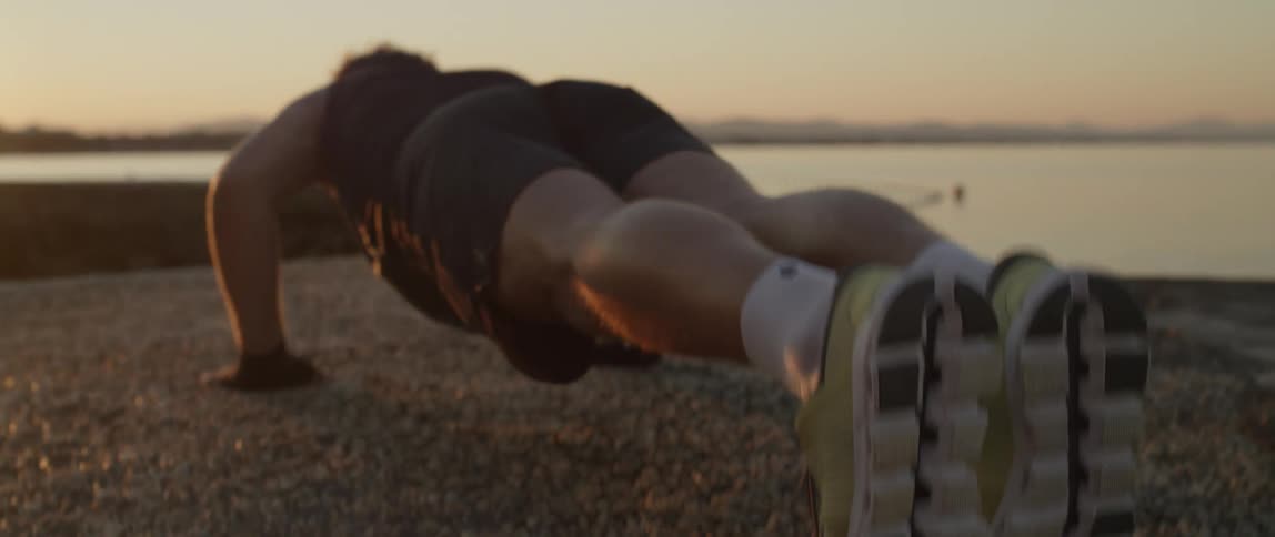 A man is doing push ups by the shore