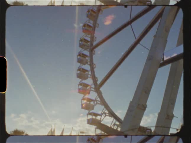 Crowd on an amusement park next to a ferris wheel at sunset