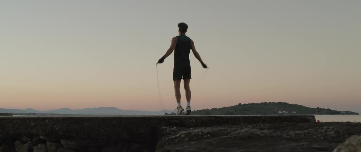 A man is jumping rope on the shore