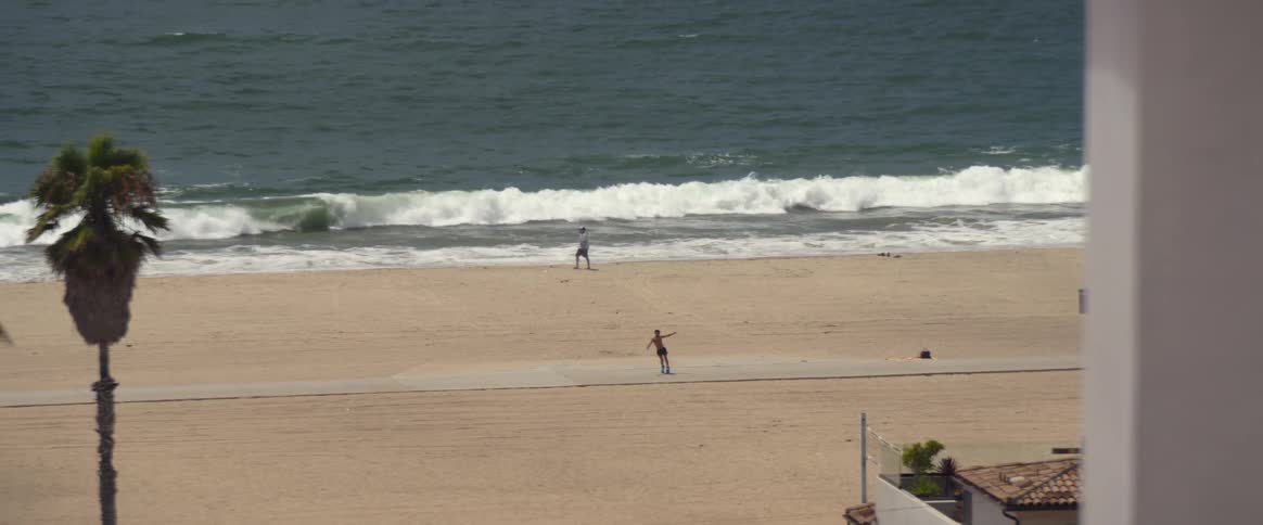 A man dancing on roller skates on the beachside sidewalk