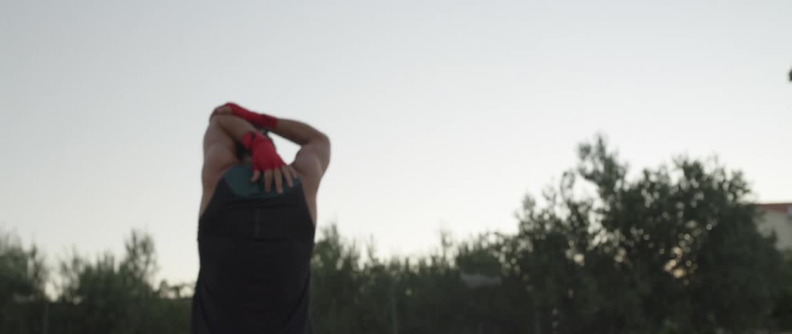 A man stretching his arms at sunset