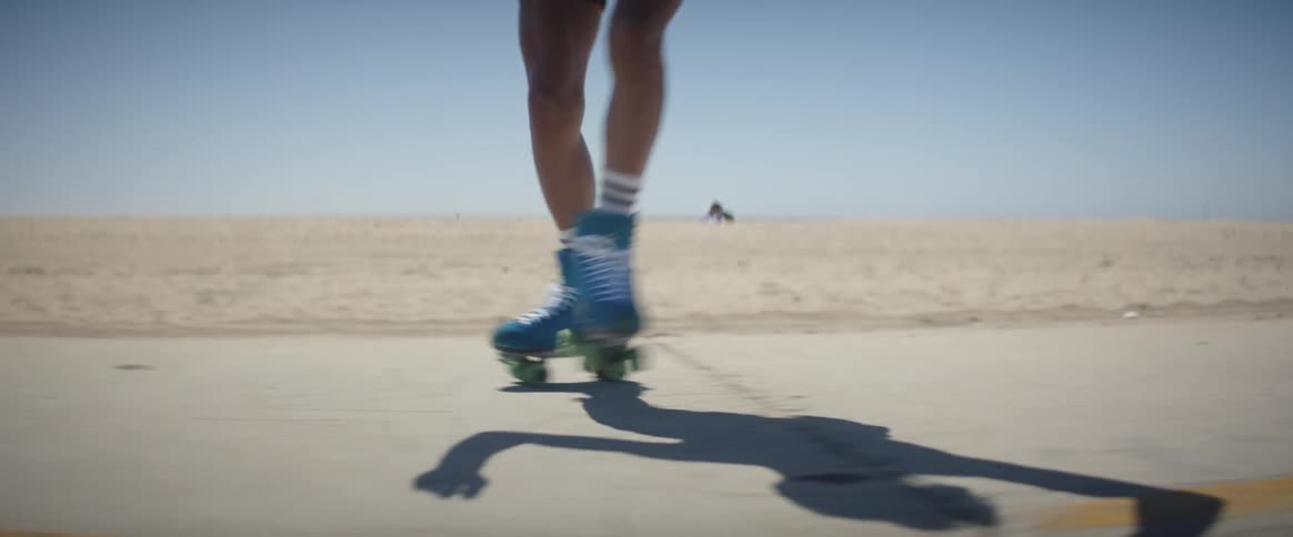 A person doing tricks with roller skates on the bike path at the beach