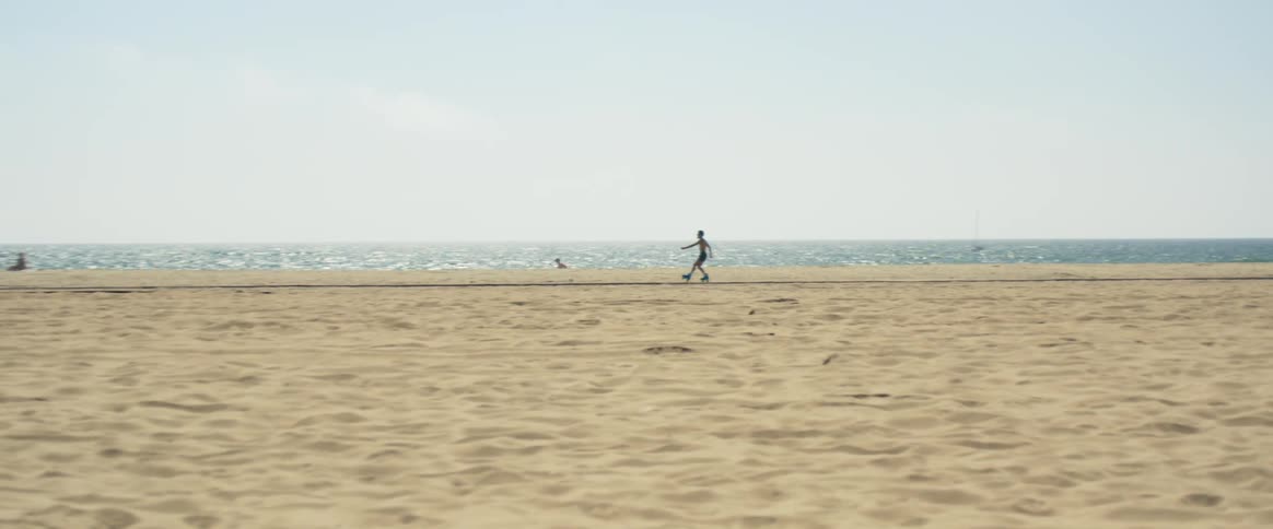 A man roller skates down a beach and then spins around and roller skates backwards