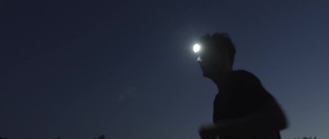 A man running with a headlamp on at dawn
