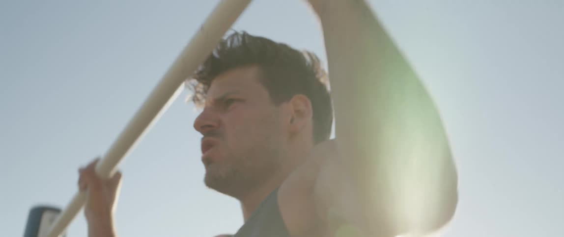 Man does pull ups outdoors on sunny day