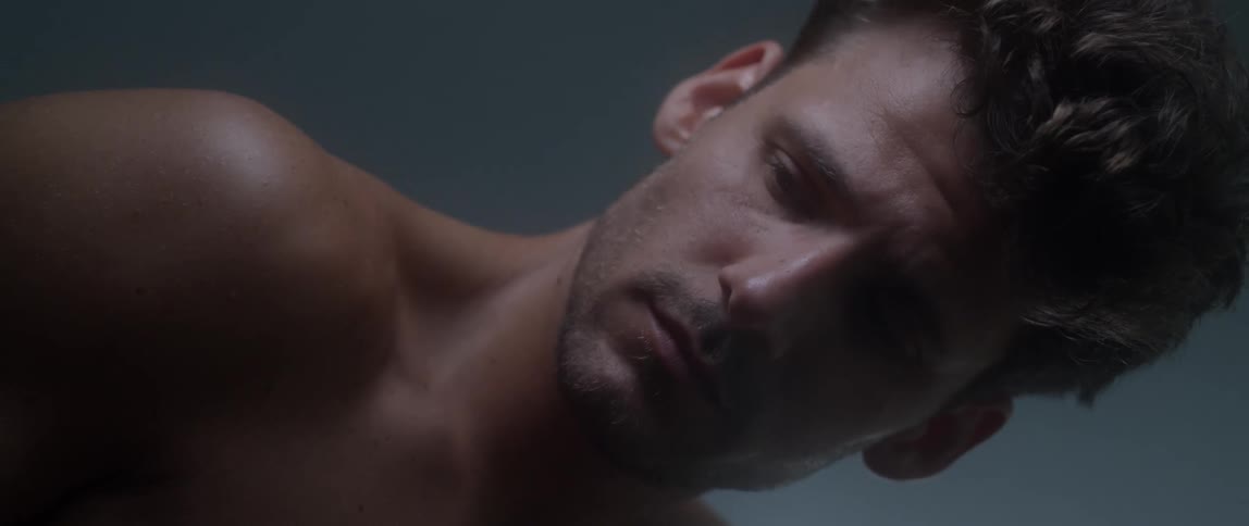 Portrait of a shirtless man running his hand across his face with a worried expression