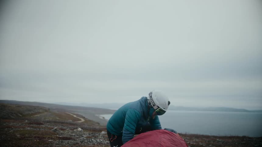 Person on hill overlooking coast packs canvas on overcast day