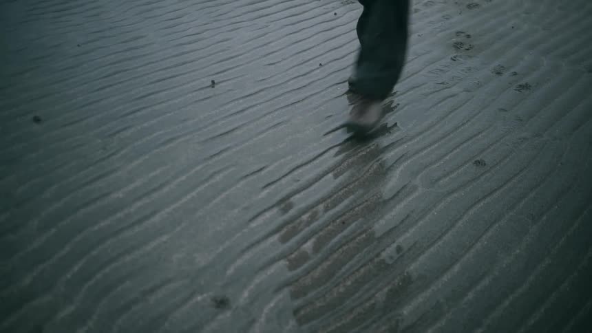 A person walking with their reflection reflecting on the wet ground