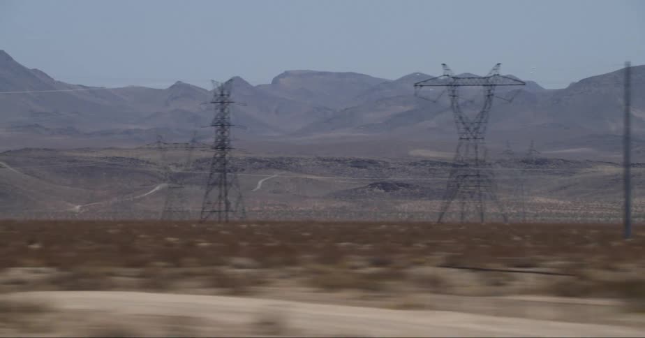 Overhead power lines and distant barren mountains in the field