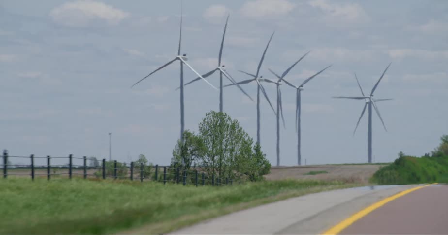 Wind turbines on wind farm seen from a vehicle driving on highway