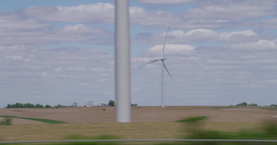 A windmill farm is shown being driven past with other vehicles passing by