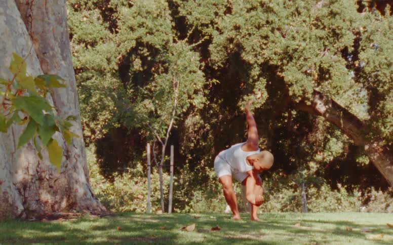 Female dancer with short hair white tank top and shorts dances at the park