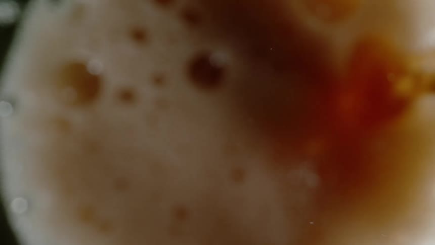 Soda pours inside a glass foaming up