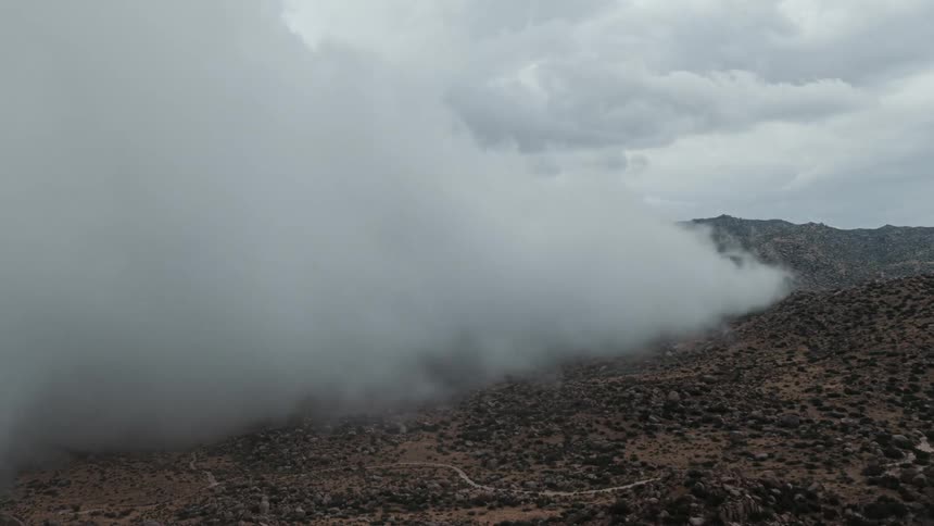 Clouds covering up barren mountain slope