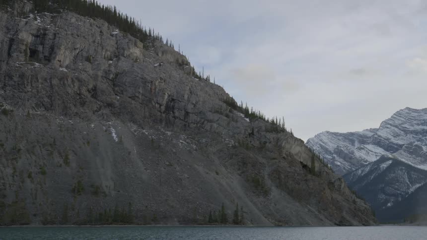 This tall mountain has trees at the top with another with snow on top