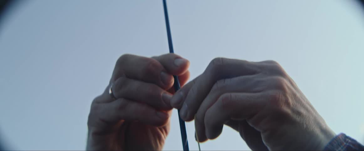 Hands string fishing line on pole