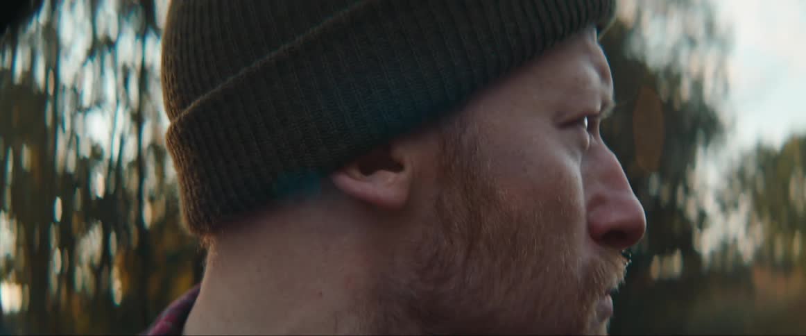 Close up of a bearded man wearing a beanie outdoors in the morning