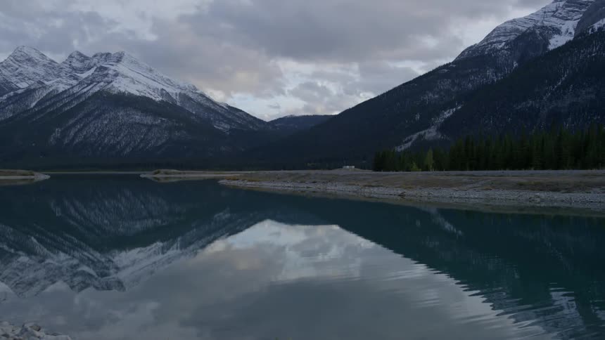 The water is calm reflecting the mountain range ahead