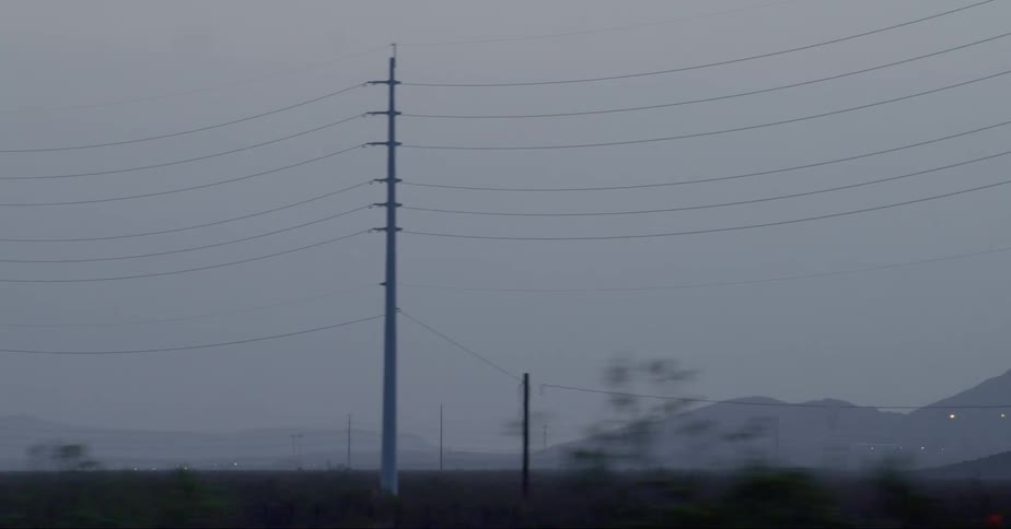 Overhead power lines seen from vehicle driving on road