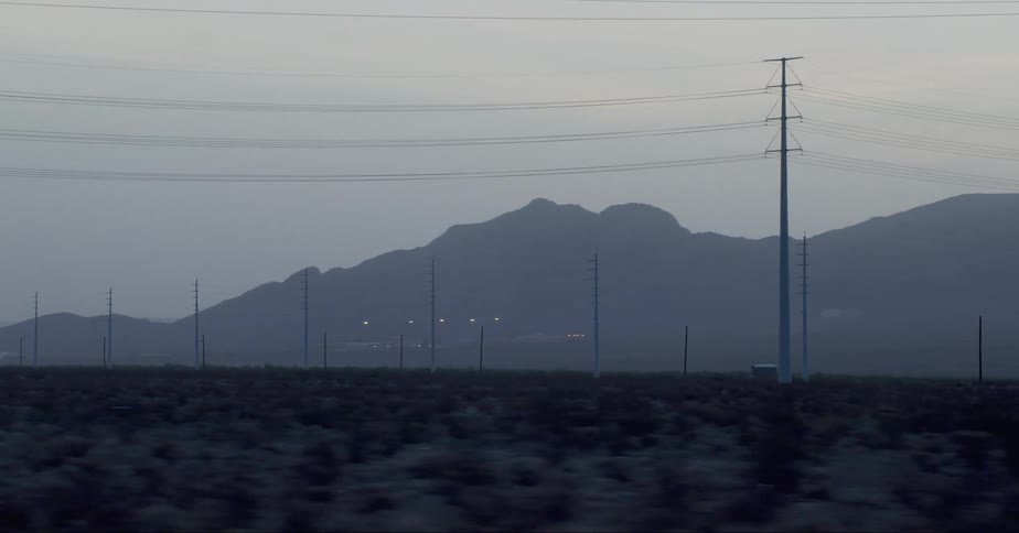 Electricity poles on a flat landscape with mountains