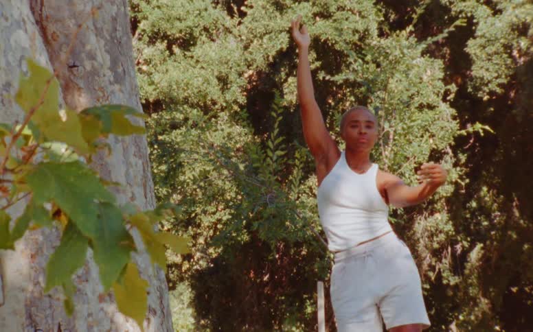 Woman dances outdoors near tree