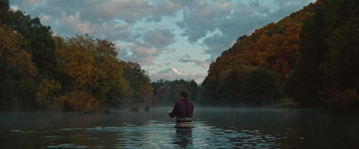 A man standing in a river and fishing from his back
