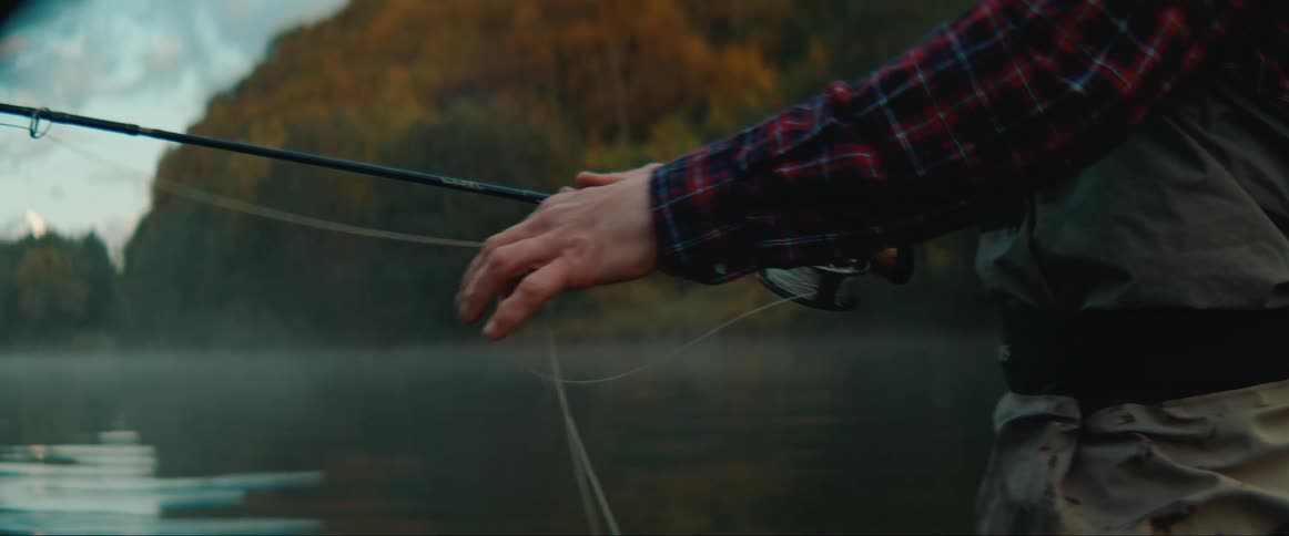 A man in a river using a fishing pole