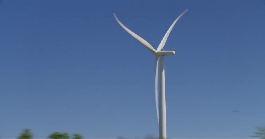Wind turbine spinning in the countryside under a blue sky