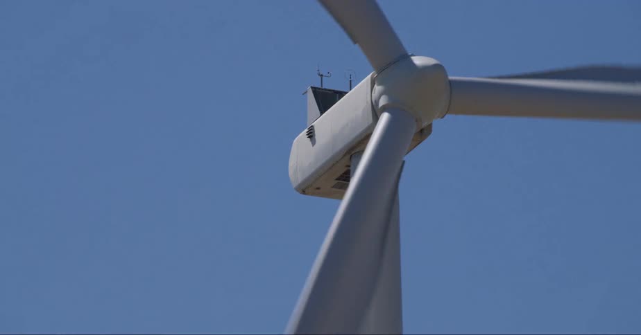 Wind turbine rotates against blue sky