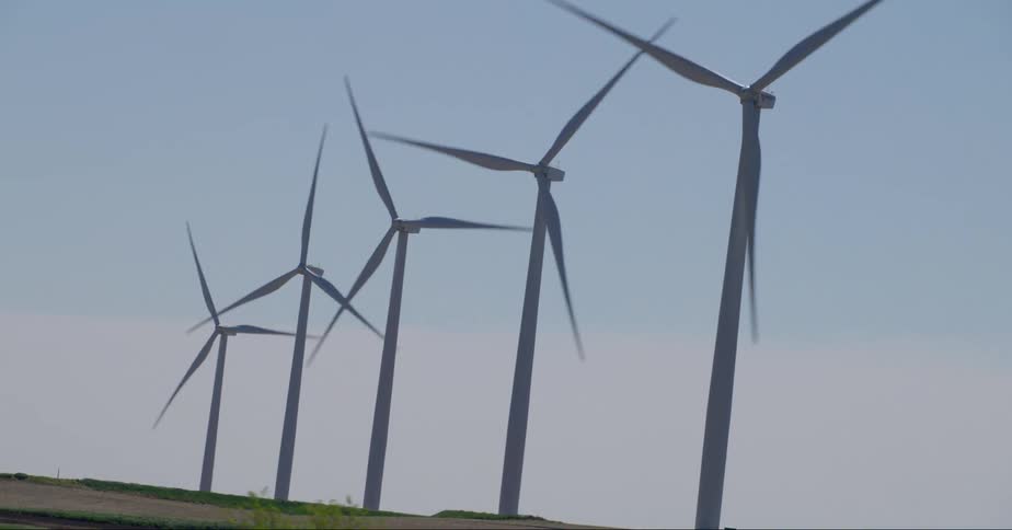 Wind turbines rotate in field during the day