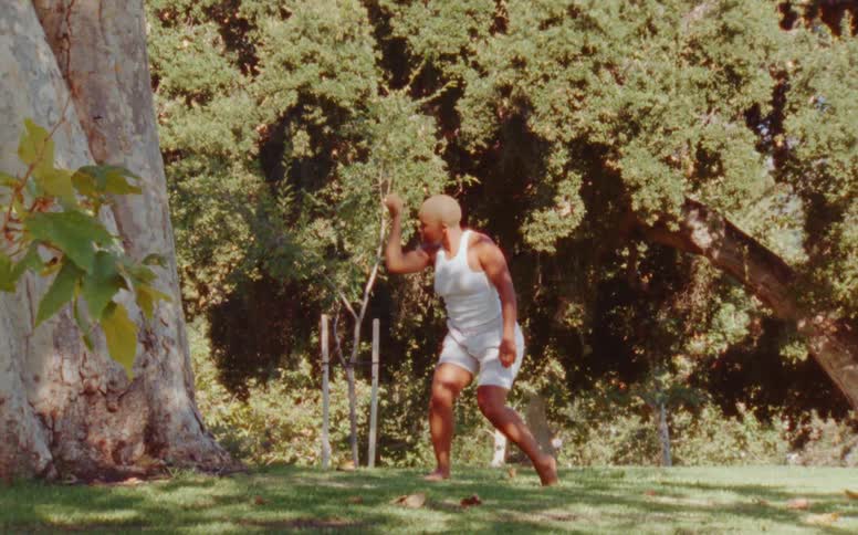 Woman dances outdoors near tree