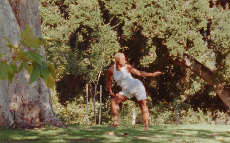Woman dances solo near trees outdoors
