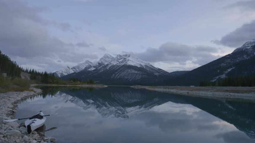 A canoe is near the side of this calm lake