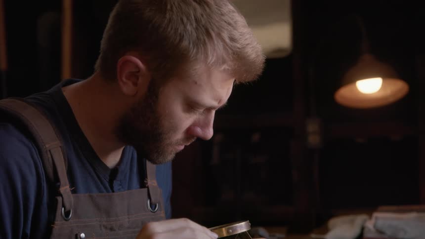 A man examines a piece of jewelry with a tool