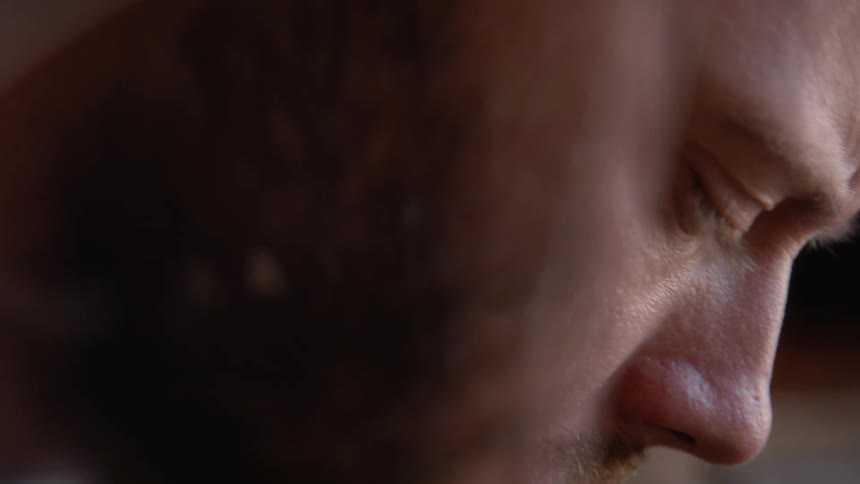 Profile of a bearded young man focused on work