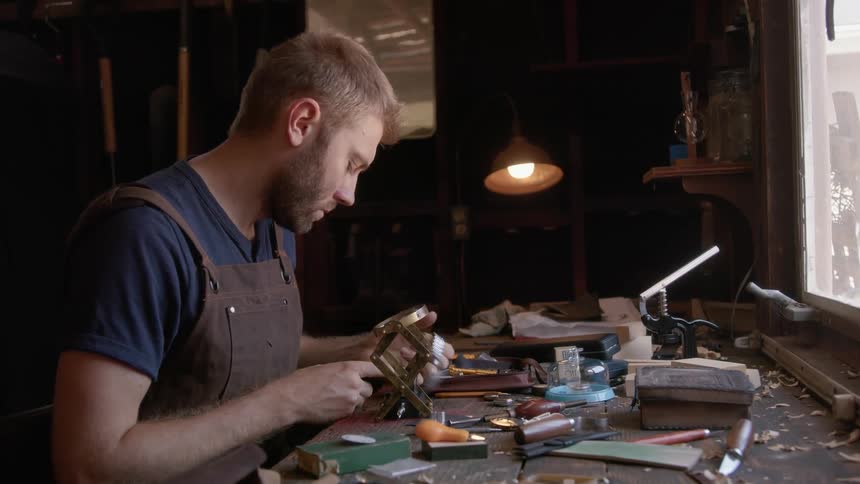 A man sits at a table fixing a wristwatch