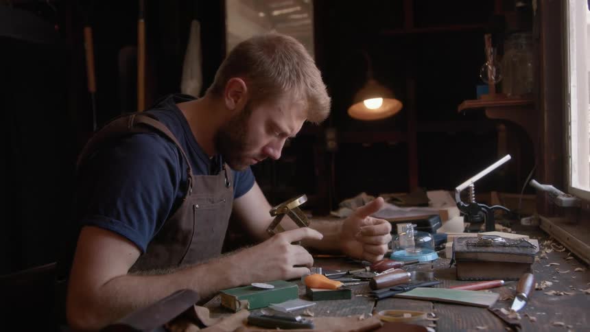 A man sitting and working with manual parts at a table
