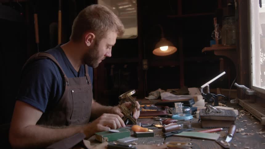 Man crafting with tools on the table while checking a watch