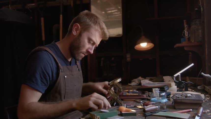 A male watchmaker pauses before resuming working on a wristwatch