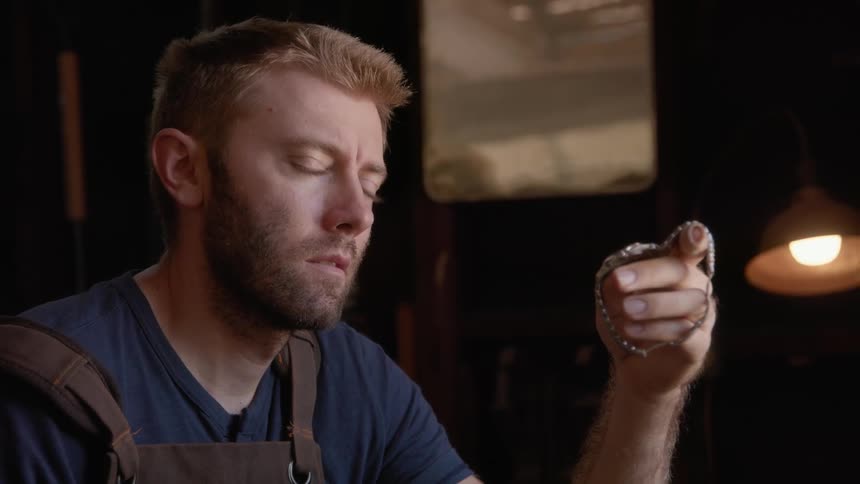 A man sitting holding a watch and deep in thought