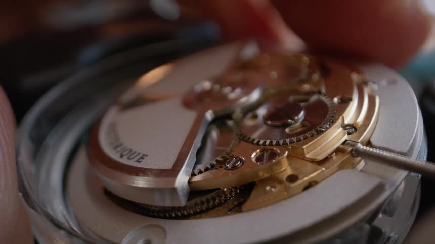 A hand places the face of a wristwatch into a small plastic circle
