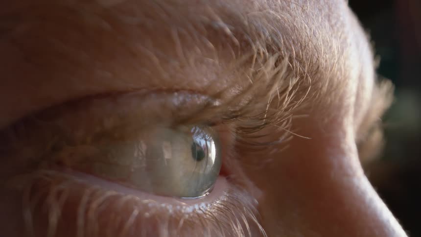 A mans eyeball moves around as he blinks while looking at his surroundings