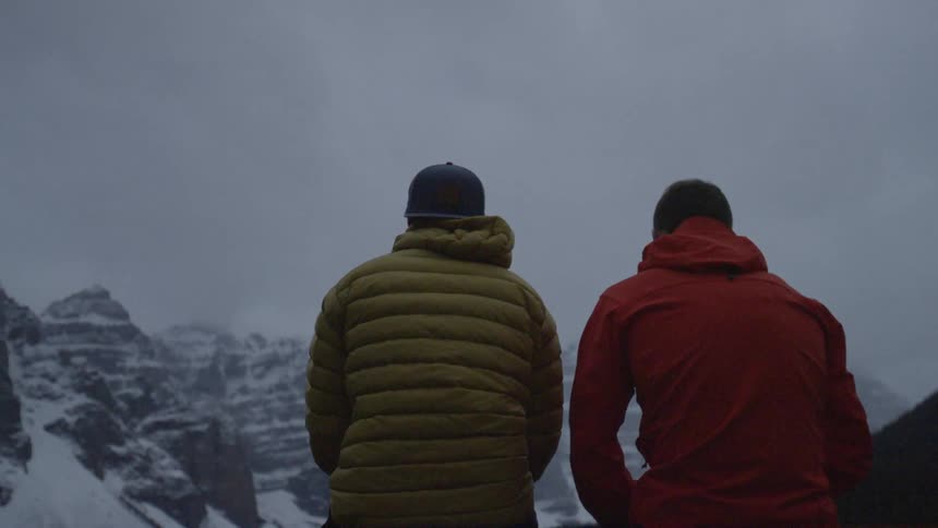 Two men are sitting on top of a mountain
