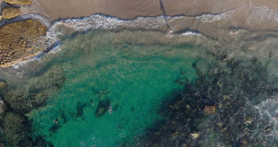 An aerial view of a turquoise blue beach with people