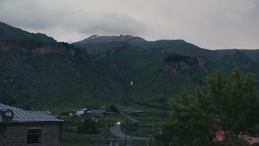 Vehicle drives along highway through rural town near mountains