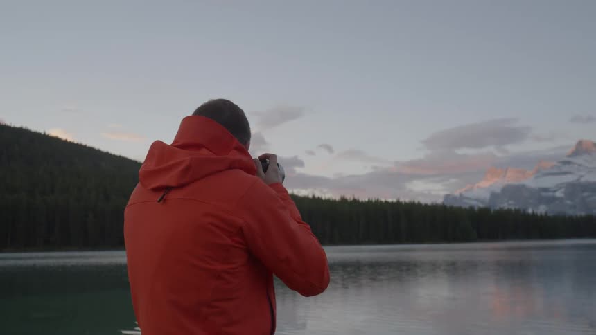 A man is taking photographs by a lake